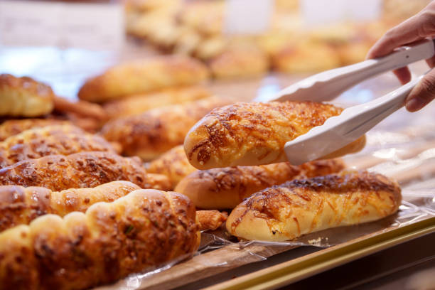 Woman selecting bread buns from bakery display